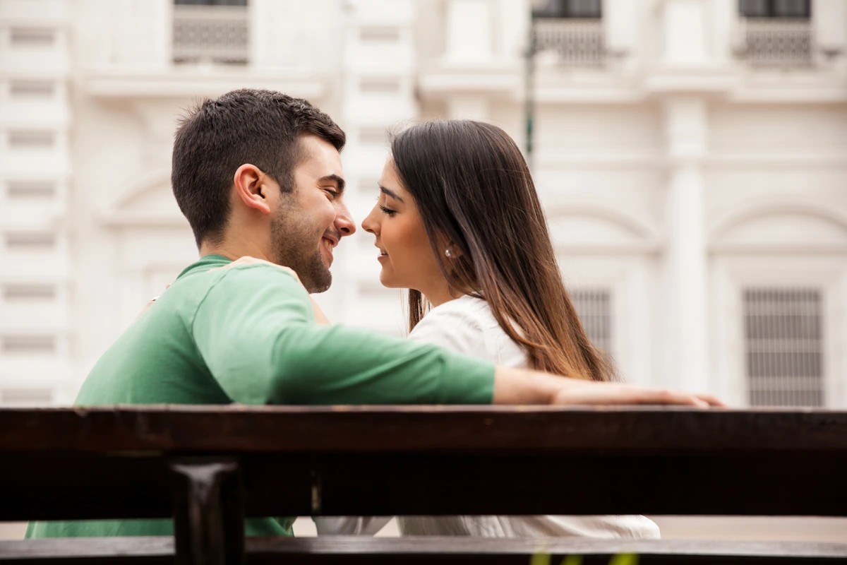 Un couple assis sur un banc sur le point de s'embrasser