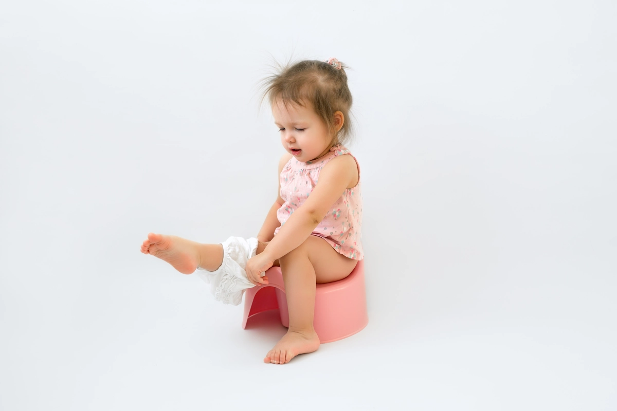 Une petite fille sur le pot qui enlève sa couche