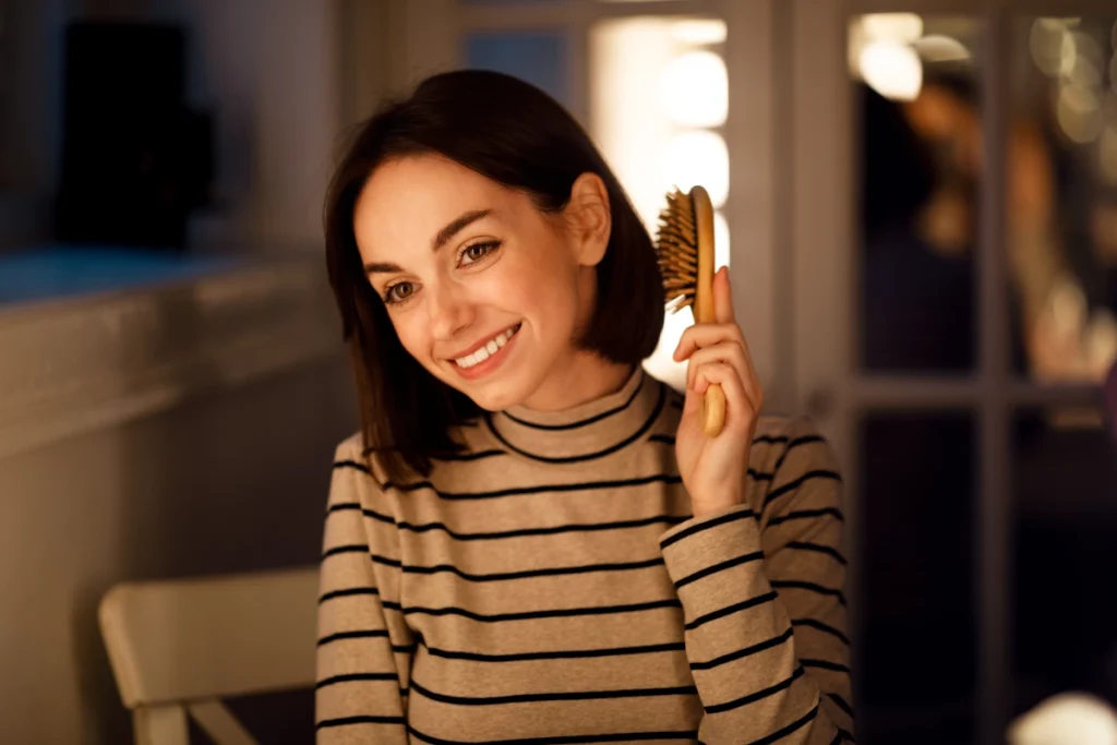 Une femme avec les cheveux courts qui se brosse les cheveux en sourire