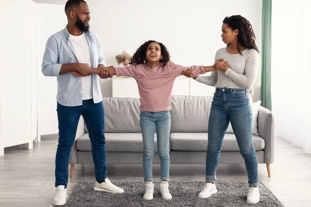 Un enfant qui est tenu par les bras par ses deux parents