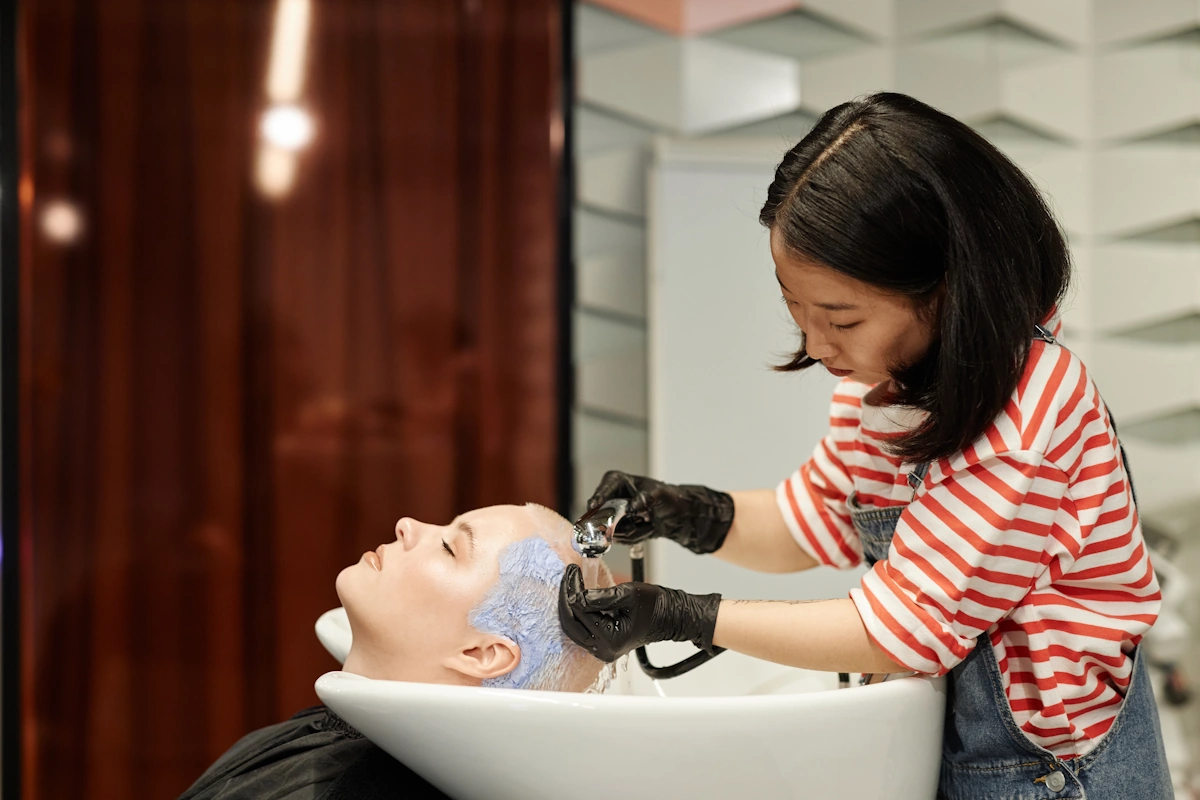 Une jeune femme qui fait un shampoing sur une autre femme avec les cheveux courts et blonds