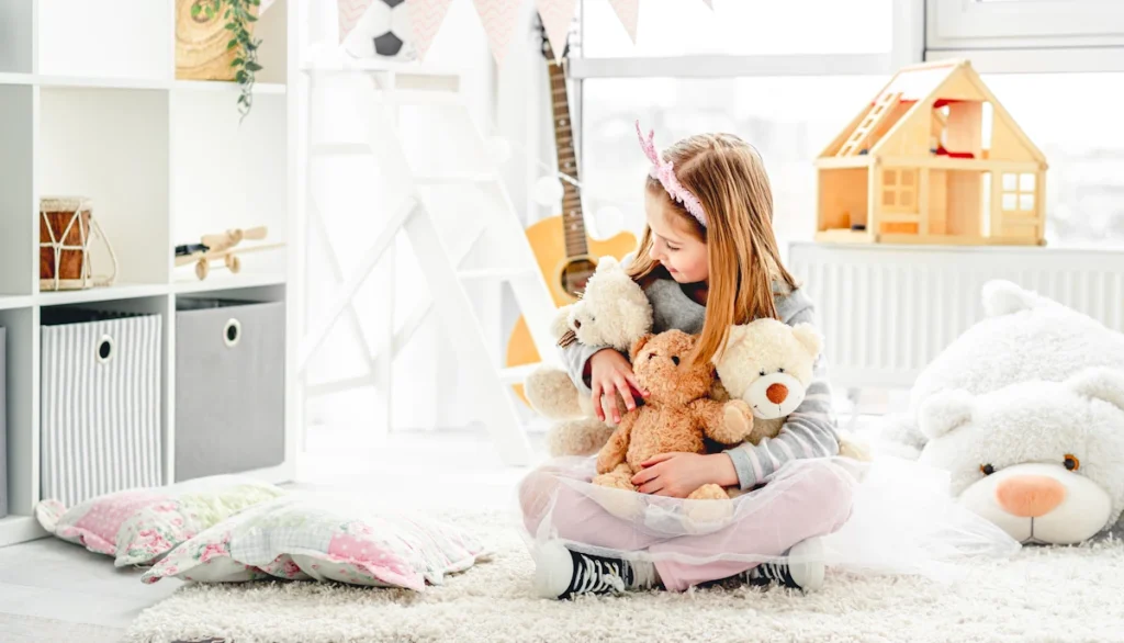 Une petite fille qui tient plusieurs peluches dans ses mains