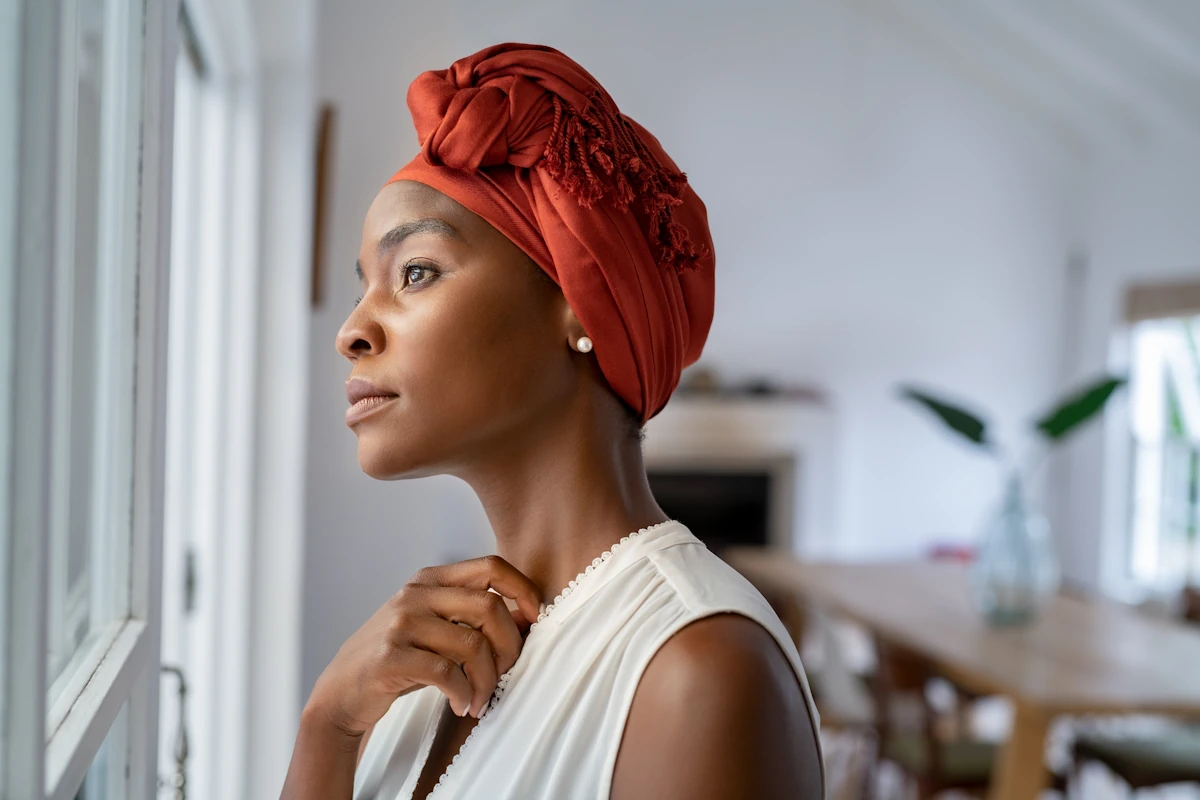 Une femme qui regarde par la fenêtre pensive