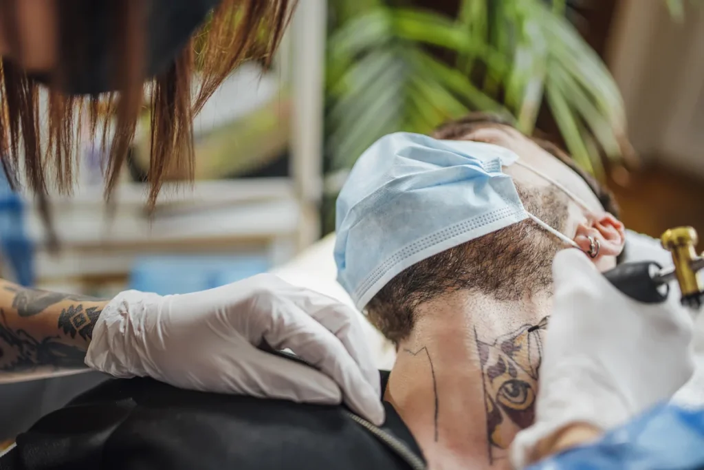 un homme qui se fait faire un tatouage au cou