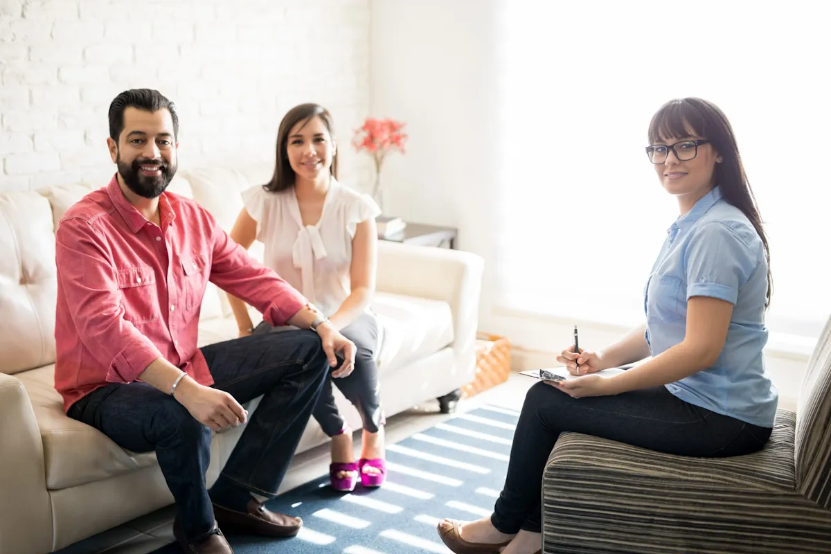 Un homme et une femme sur un canapé face à une femme qui prend des notes
