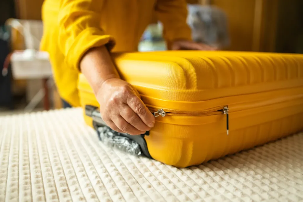 Une personne qui ferme une valise jaune