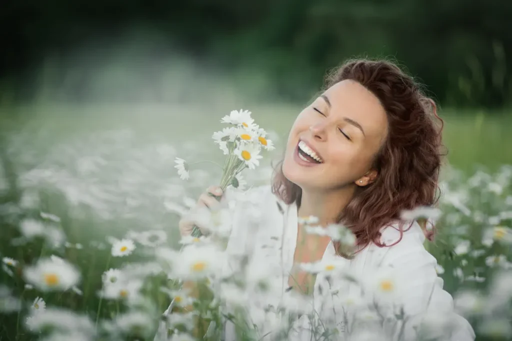 Une femme qui sourit assise entre les fleurs