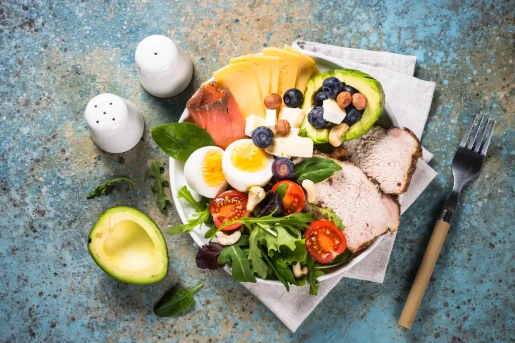 Une assiette d'oeuf, de viande avec des légumes verts avec de l'avocat et d'autres baies