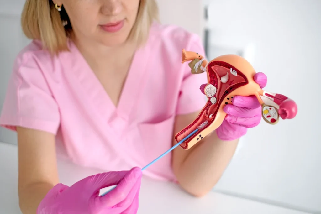 Une efmme médecin en tenue rose qui montre la pose d'un stérilet