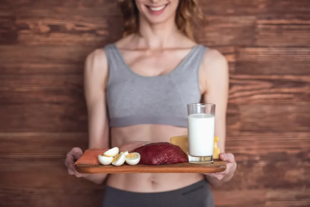 Une femme qui tient u plateau avec de la viande, des œufs et un verre de lait