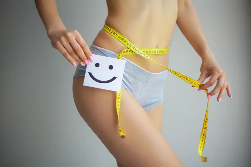 Une femme qui tient un mètre ruban autour de ses hanches et une petite carte avec un smiley