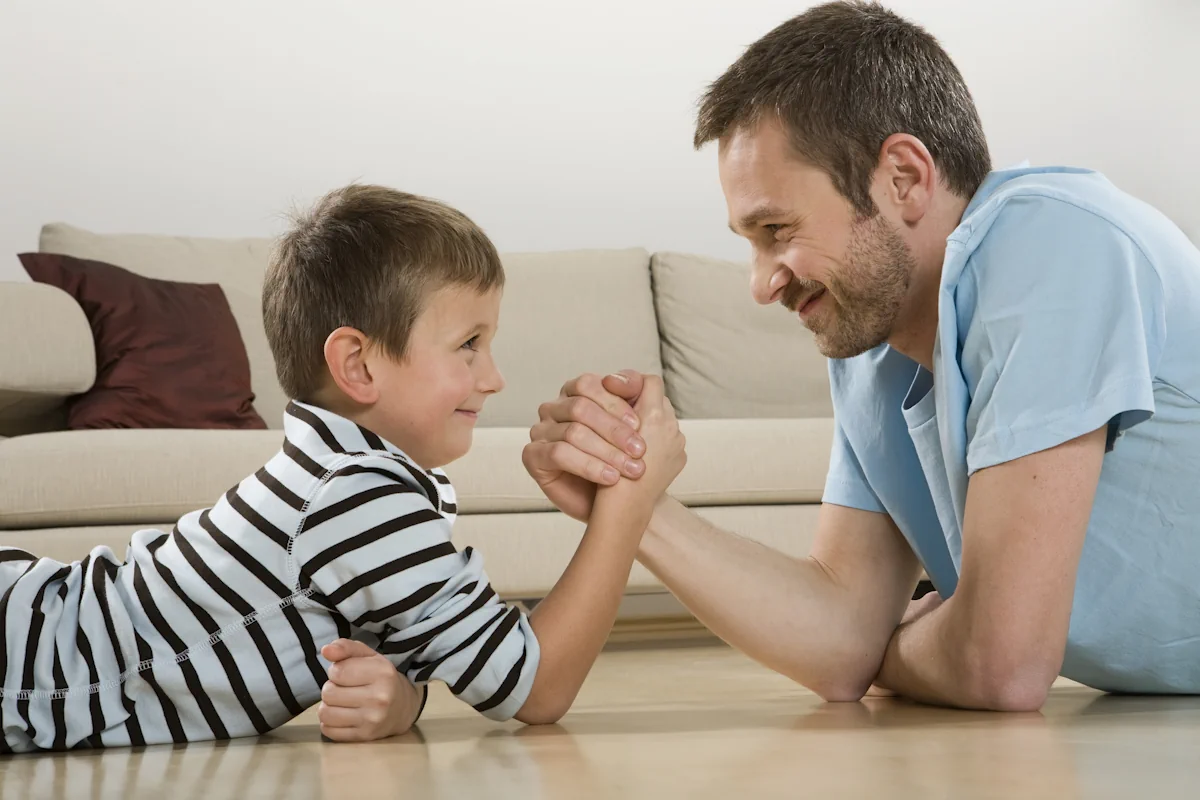Un homme et un petit garçon qui fait un bras de fer avec le sourire