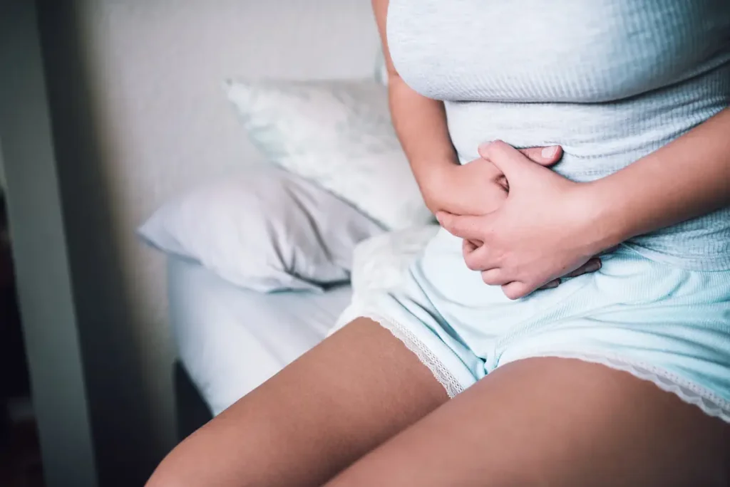 Une femme qui se tient le ventre avec ses deux mains