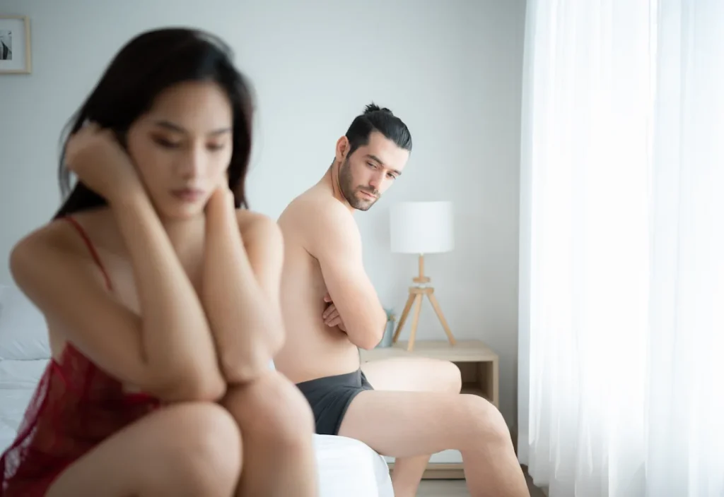 Un homme et une femme en petite tenue assis de chaque côté du lit
