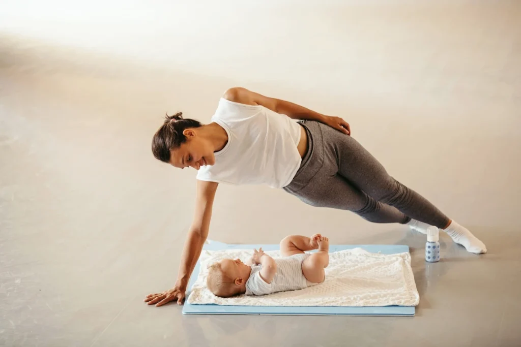 Une femme qui fait la planche avec son bébé sur le sol