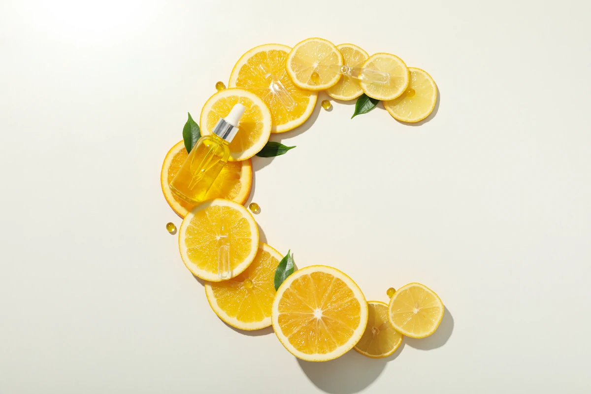 Des oranges coupées en rondelles qui forme la lettre C avec un flacon de produit jaune