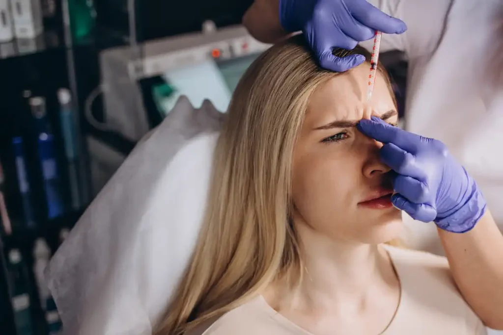 Une femme avec une seringue de botox dans le front