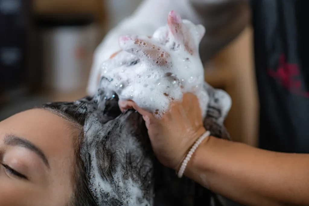 Une femme qui fait un shampoing sur ses cheveux qui moussent