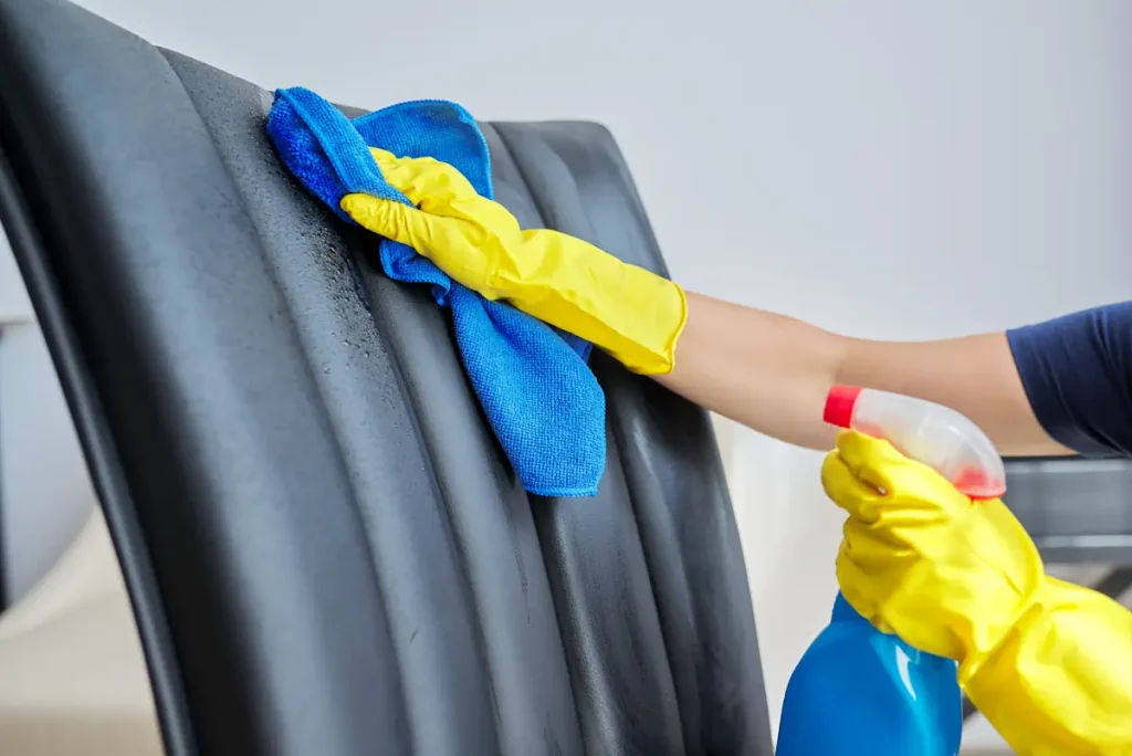 Une personne qui porte des gants jaunes qui nettoie une chaise en cuir