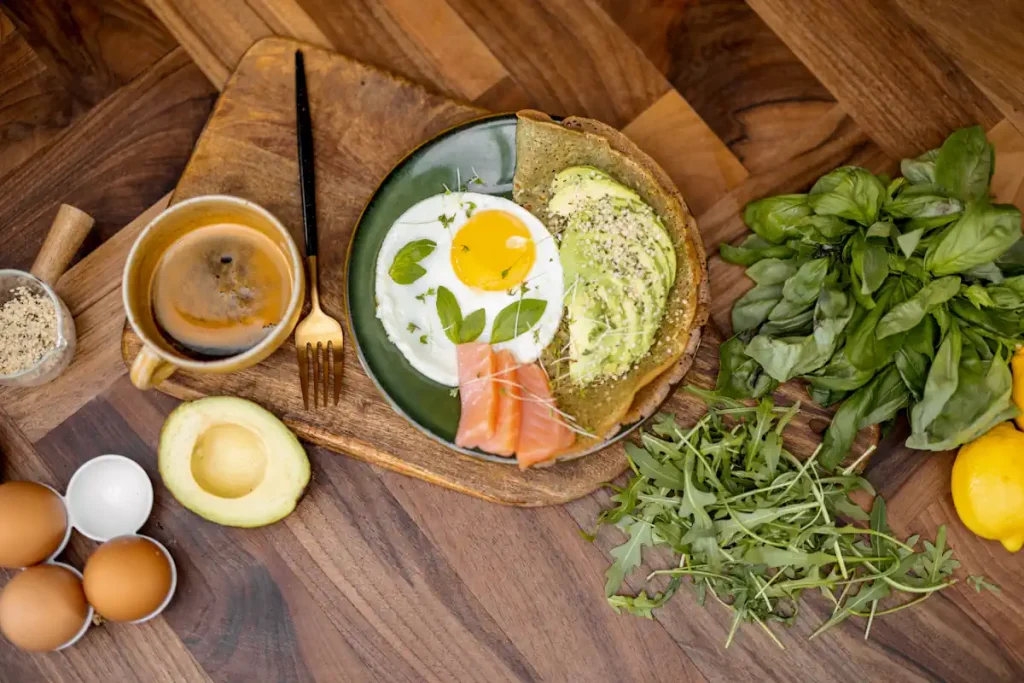 Une assiette avec un œuf, de l'avocat, du poisson, des légumes verts, etc.