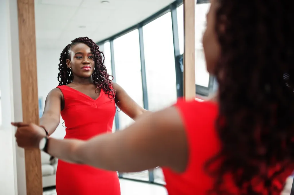 Une femme en robe rouge qui se regarde dans un miroir