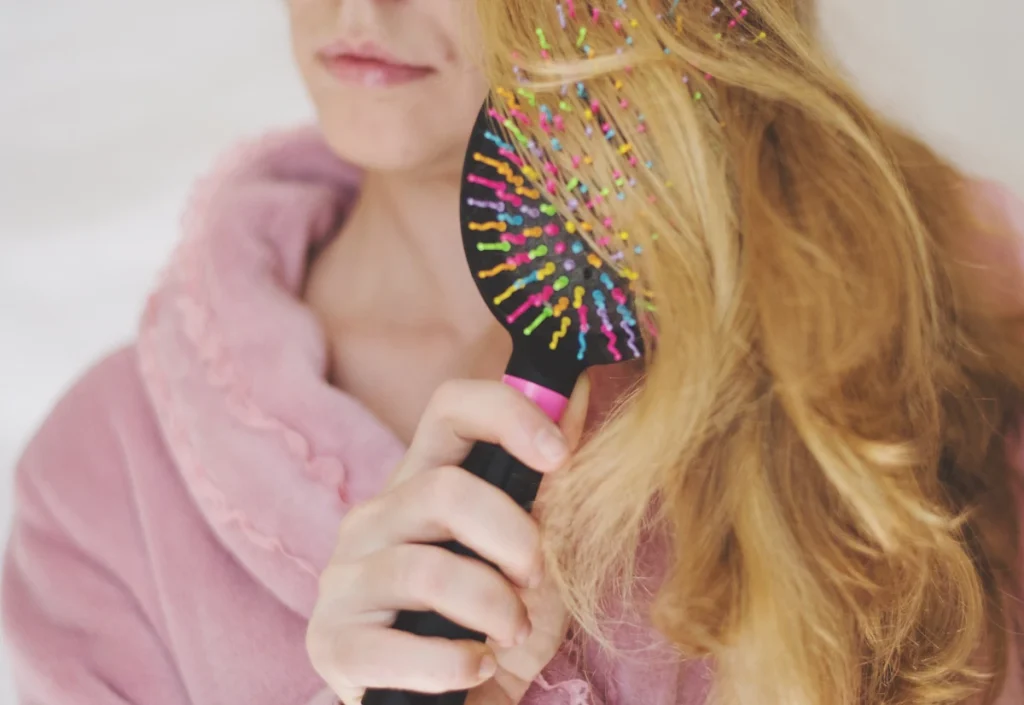 Une femme qui se brosse les cheveux avec une brosse