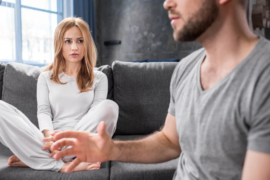 Une femme assise sur le canapé qui regarde un homme