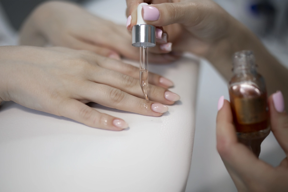 Une personne qui applique de l'huill sur les ongles d'une autre personne