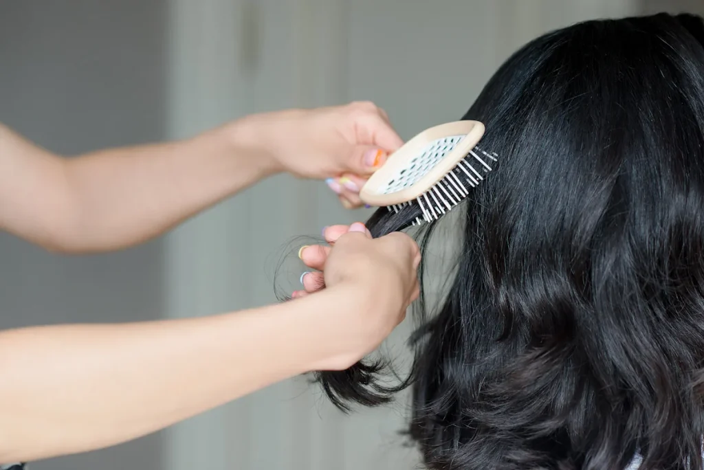 Une personne qui brosse les cheveux d'une femme avec une brosse