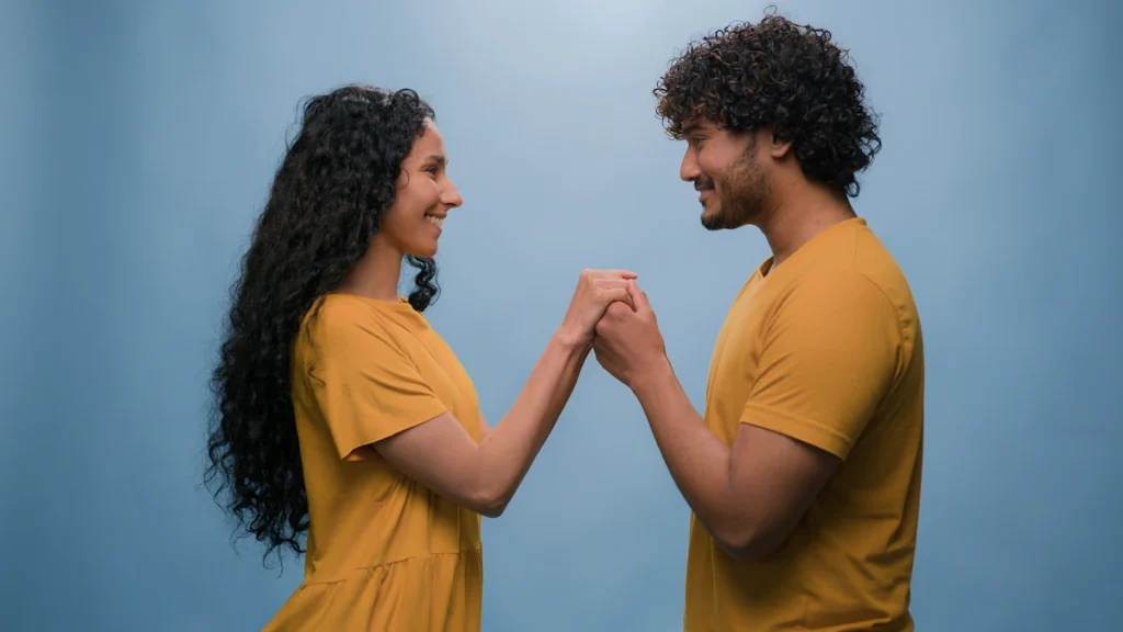 Un homme et une femme qui se tient la main et qui se regarde en sourriant