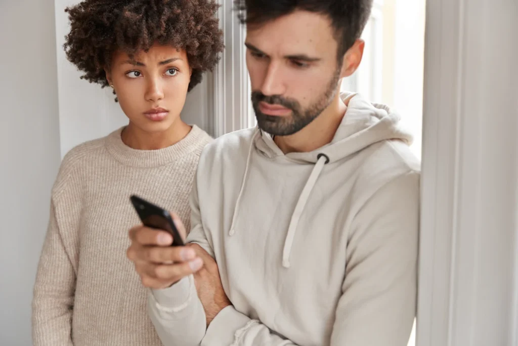 Un homme qui regarde son téléphone avec une femmederrière qui regarde