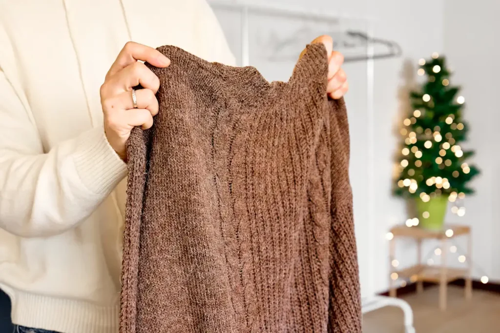 Une personne qui tient un pull marron