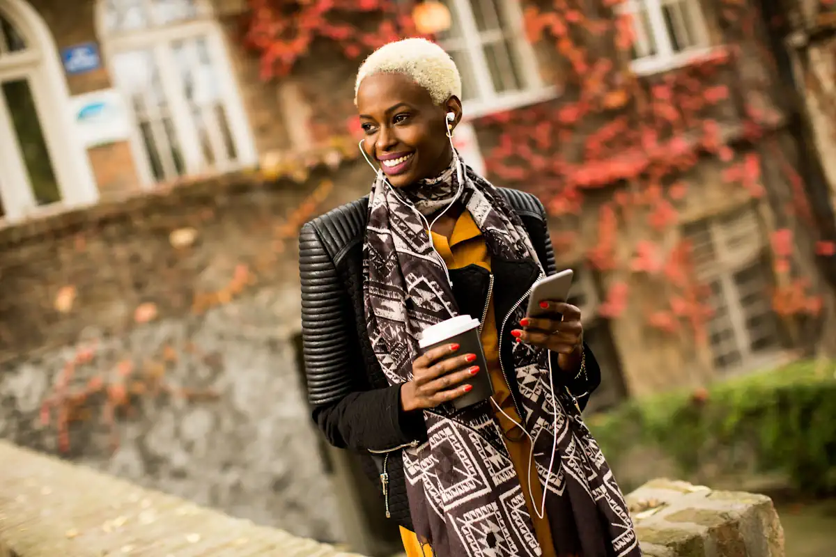 Une femme stylée ave un café et un smartphone dans la main