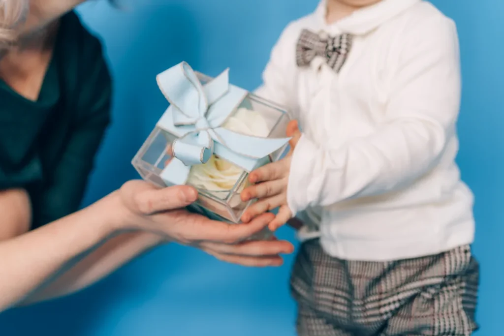 Un petit garçon qui reçoit un cadeau avec un nœud bleu de la part d'une femme
