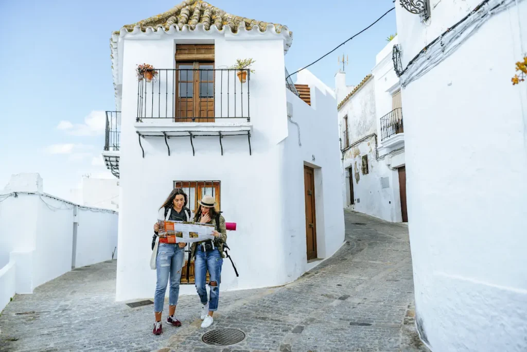 Deux jeunes femmes qui regarde une carte au milieu d'un village de maison blanche