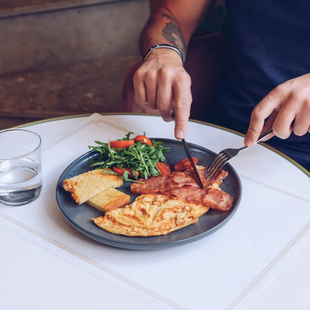 Une personne qui mange une assiette d'œufs et de viandes