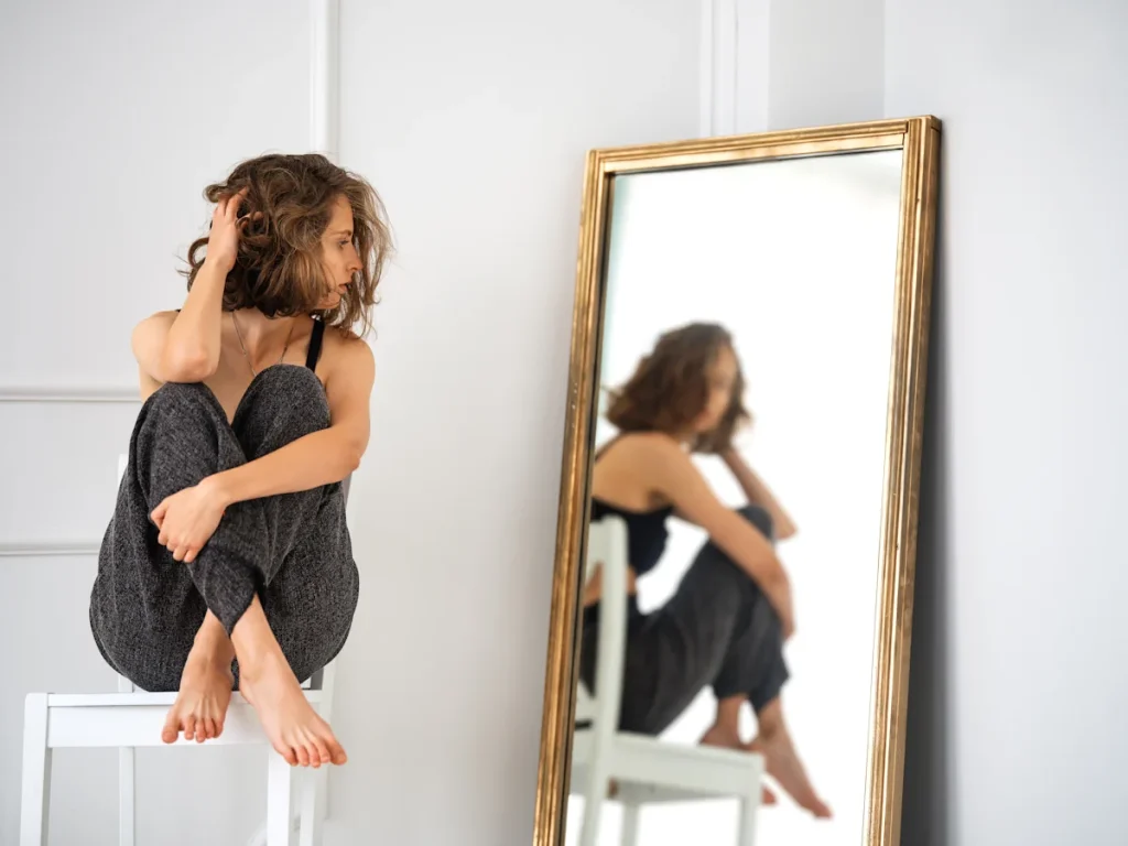 Une femme assise qui se regarde dans le miroir