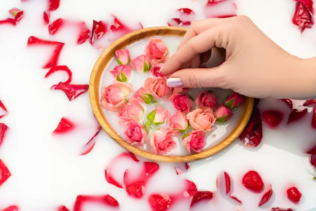 Une personne qui prend des boutons de rose plongée dans un liquide blanc