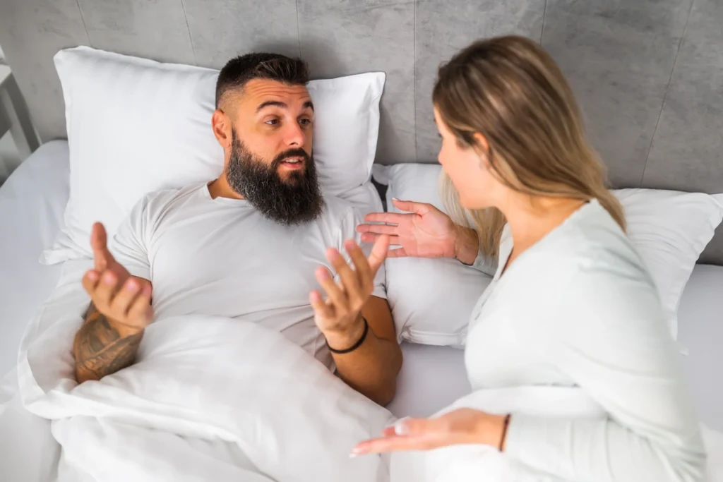 Un homme et une femme qui discute dans un lit