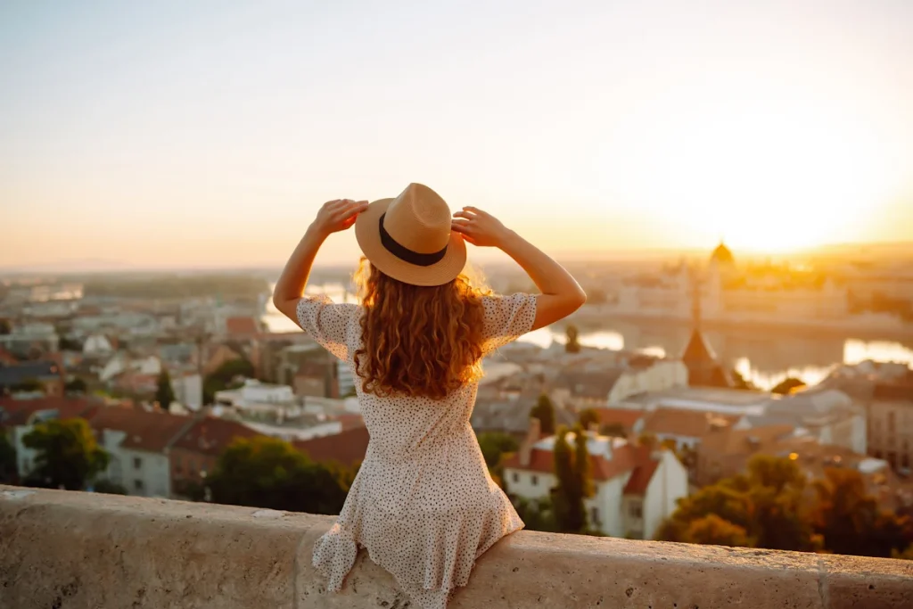 Une femme avec un chapeau assise face à une ville