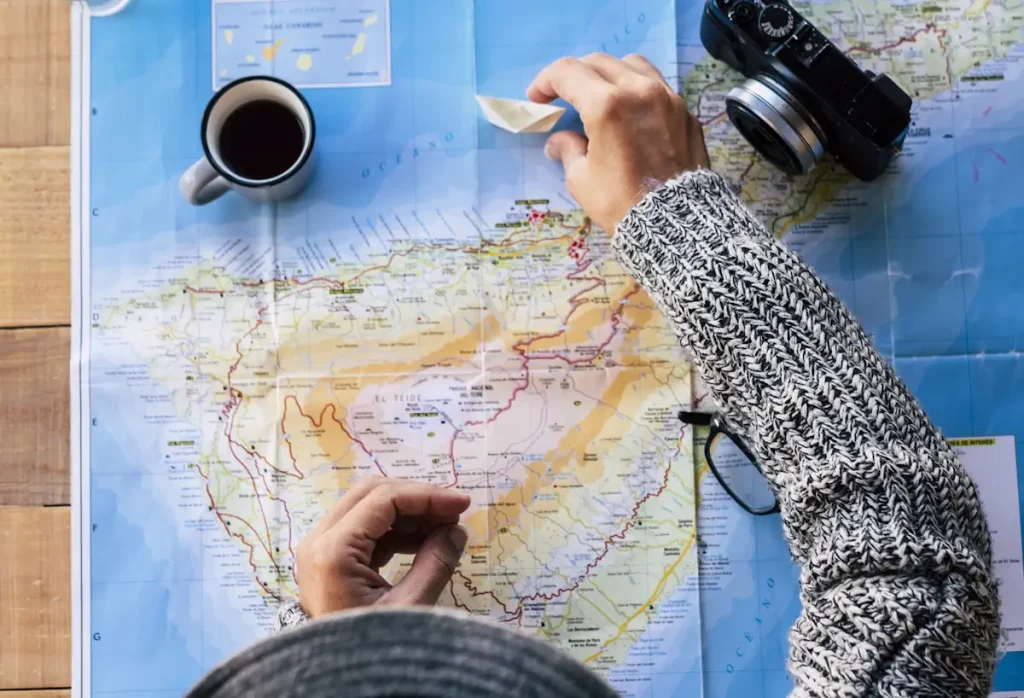 Une femme qui regarde une carte avec son tasse de café et son appareil photo sur la table