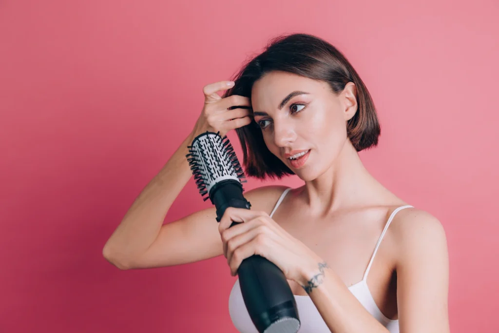 Une femme qui se brosse les cheveux ave une brosse chauffante