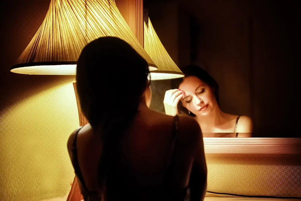 Une femme dans le noir qui se regarde dans un miroir