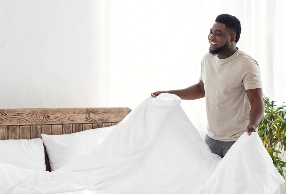 Un homme qui met de nouveau drap sur le lit