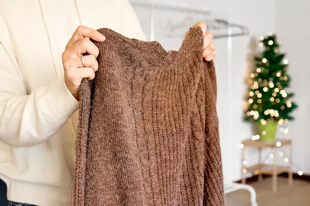 Une personne qui tient un pull marron dans sa main