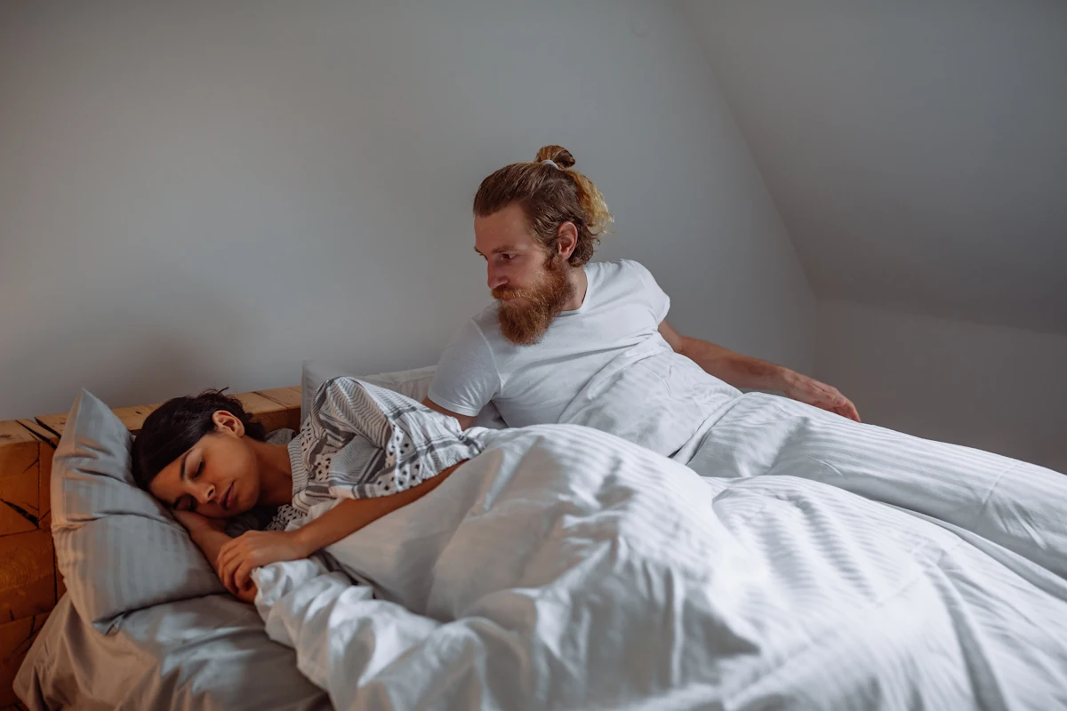 Un homme qui regarde une femme endormit à côté de lui