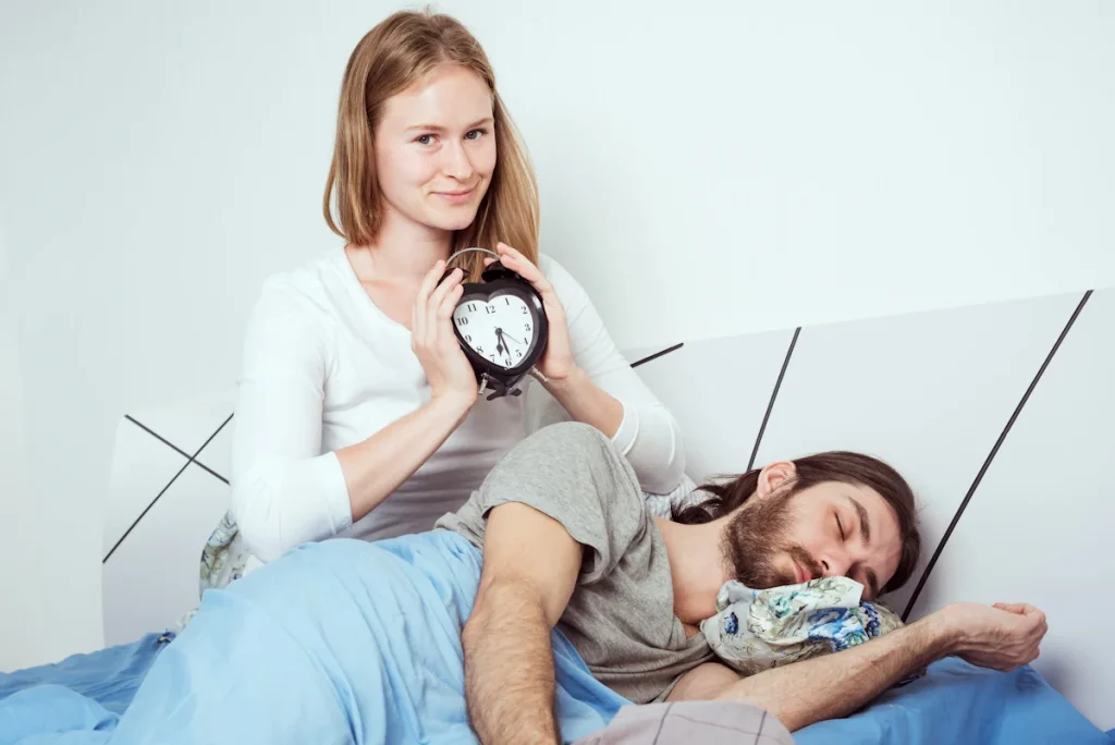 Une femme qui réveille un homme avec un réveil